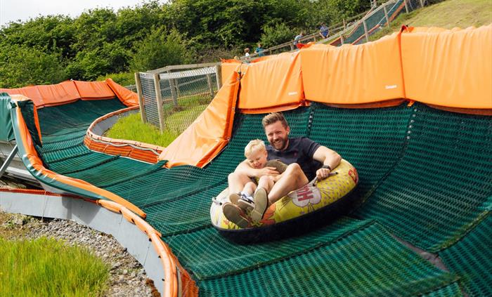 A father and son laughing in the tube as the ride finishes.